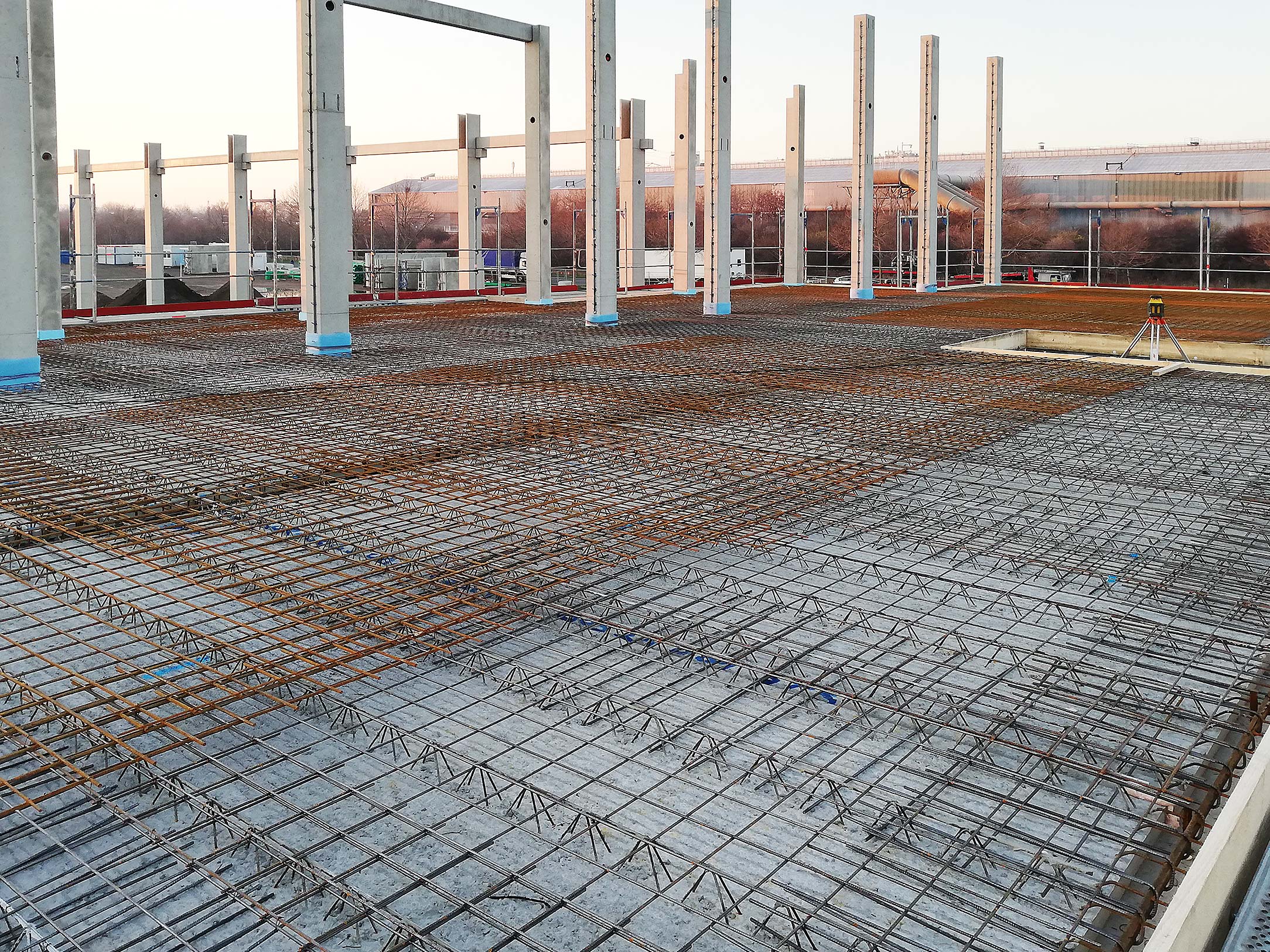 Baugrund mit Betonstahlmatten und Stahlstützen bei Sonnenuntergang auf einer Baustelle.
